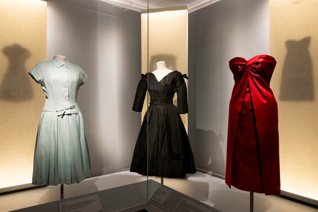 Trois robes, bleu, noir et rouge, dans une vitrine d'exposition