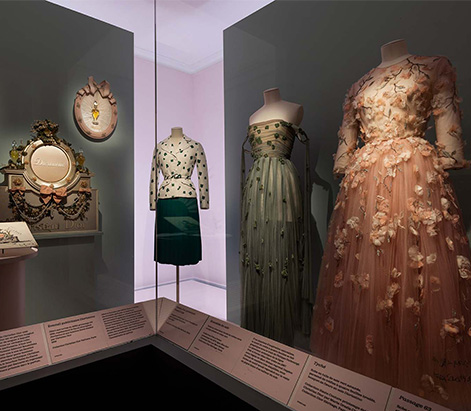Expo 2025 - Diorissimo Trois robes dans une vitrine pour l'exposition de 2025
